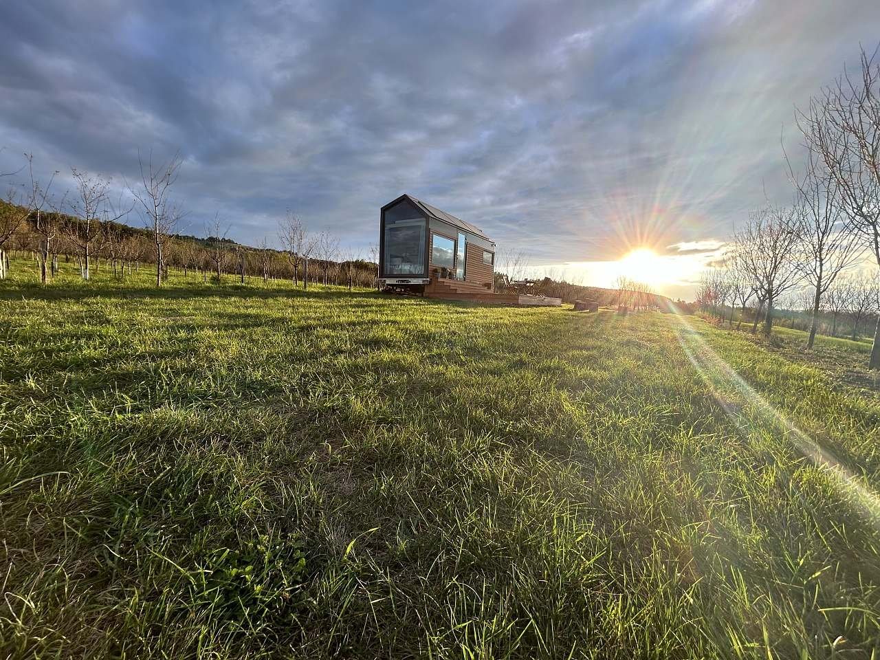 Tiny house Glampidol v trnkovém sadu, slunce nad kopci