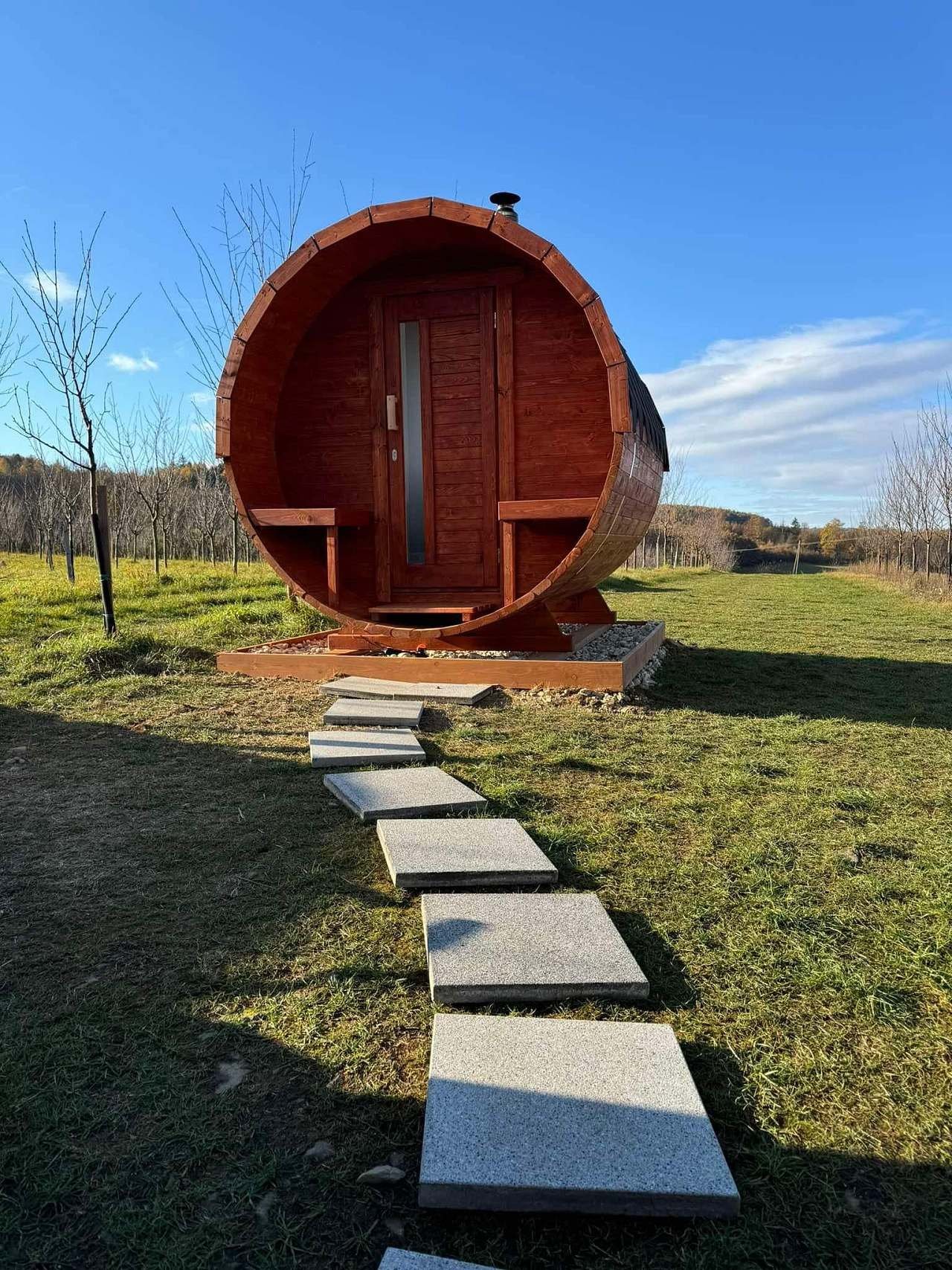 Sudová sauna na trávníku, k ní vedou kamenné nášlapy